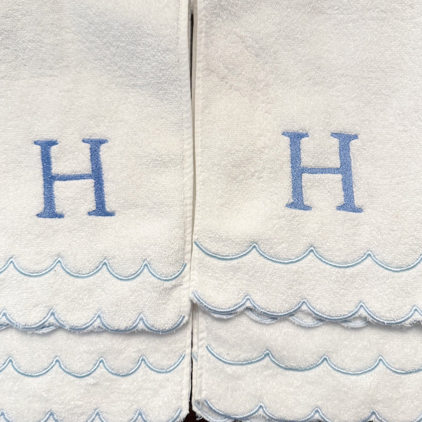 White towels with blue wave patterns and 'H' letters on a white background