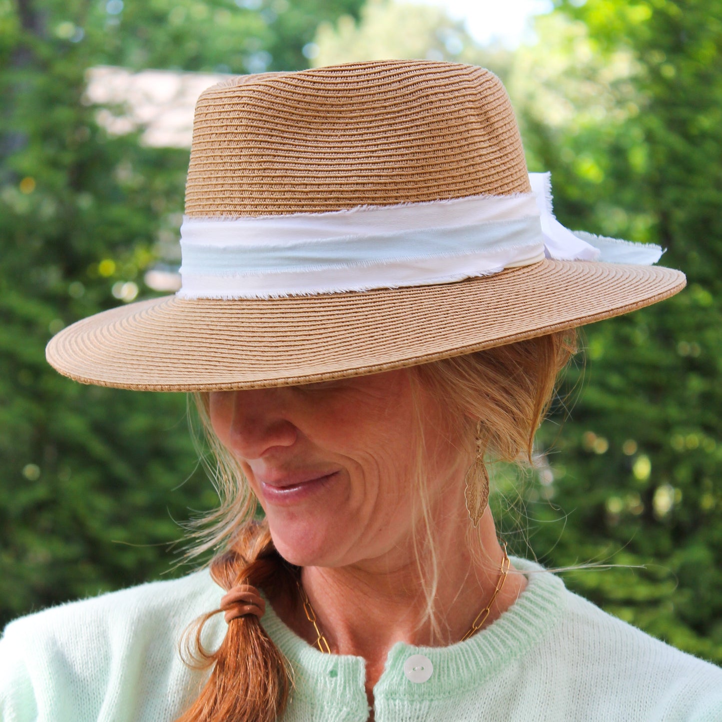 Woman wearing a straw hat with a white band outdoors