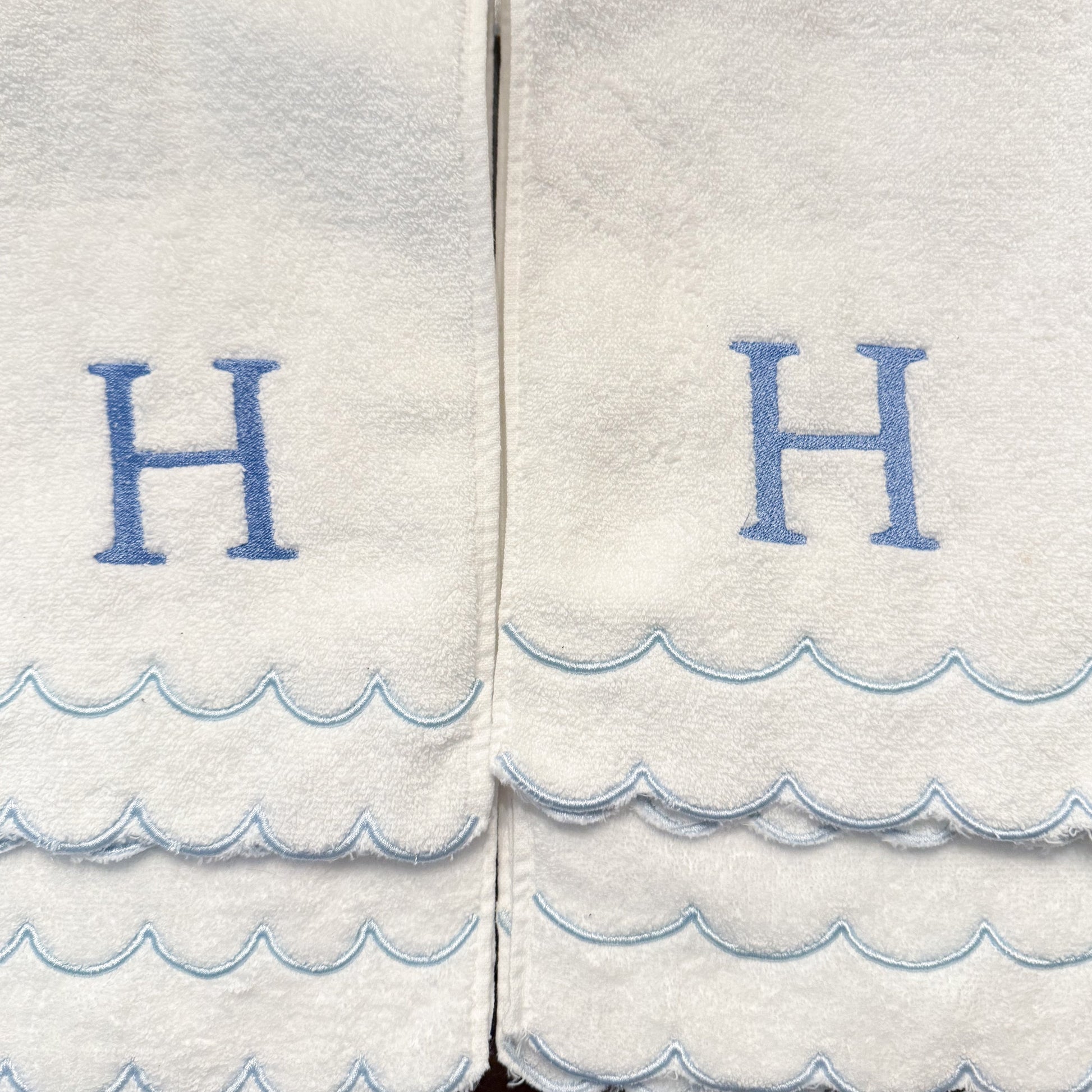 White towels with blue wave patterns and 'H' letters on a white background