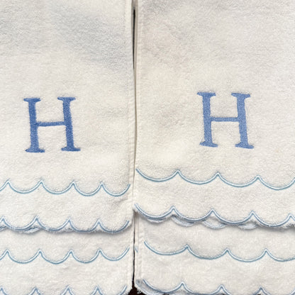 White towels with blue wave patterns and 'H' letters on a white background